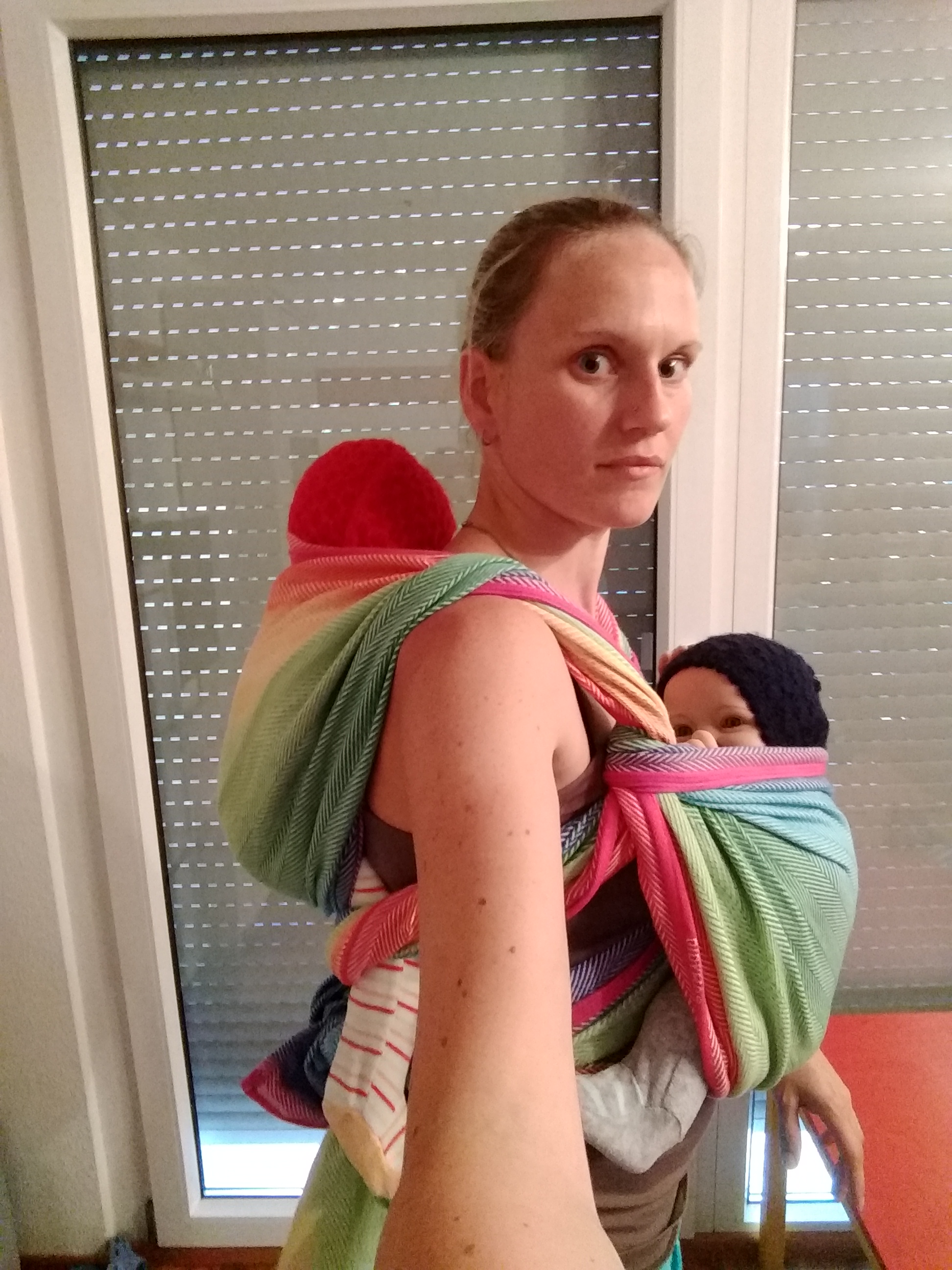 Zwillingsbindeweise mit einem Tuch - ein Baby im einfachen Rucksack auf dem Rücken, das andere vorn im Kreuz